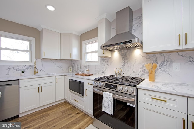 508 Vine St, Palmyra, NJ 08065 - kitchen with stainless steel appliances, wall chimney exhaust hood, light stone counters, light wood-style flooring, and white cabinets