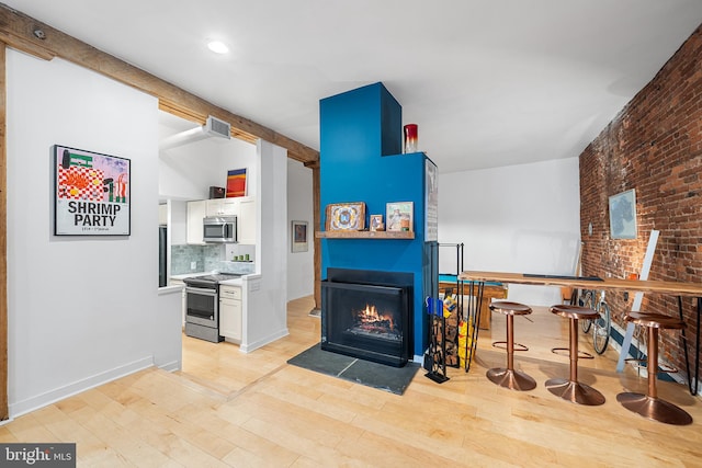 114 Naudain St Unit A, Philadelphia, PA 19147 - living area with a fireplace with flush hearth, light wood-type flooring, brick wall, and recessed lighting