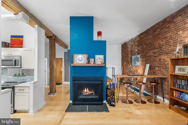 114 Naudain St Unit A, Philadelphia, PA 19147 - living area featuring light wood finished floors, brick wall, and a fireplace with flush hearth