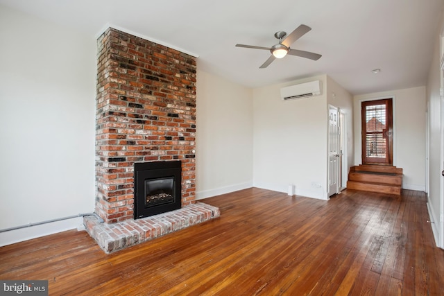 1240 Girard St NW, Washington, DC 20009 - unfurnished living room with a wall mounted AC, hardwood / wood-style flooring, a brick fireplace, and ceiling fan