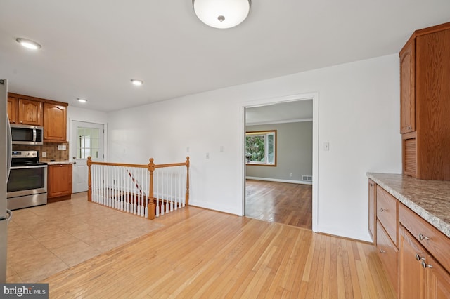 814 Manhattan Beach Rd, Severna Park, MD 21146 - kitchen with stainless steel appliances, backsplash, light countertops, brown cabinetry, and light wood-style flooring