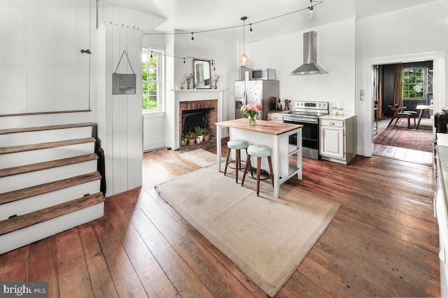 1498 Mckinstrys Mill Rd, Union Bridge, MD 21791 - kitchen with wall chimney range hood, stainless steel appliances, butcher block counters, dark wood-type flooring, and a breakfast bar area