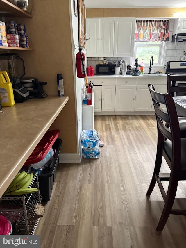 2212 Cove Rd, Pennsauken, NJ 08110 - kitchen featuring black microwave, exhaust hood, white cabinetry, light wood-type flooring, and light countertops