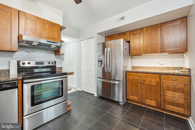 9810 Kingsbridge Dr Unit 102, Fairfax, VA 22031 - kitchen featuring stainless steel appliances, under cabinet range hood, brown cabinetry, and dark stone countertops