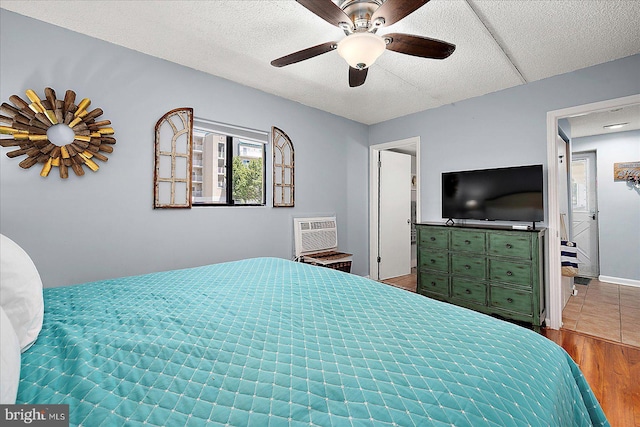 14 136th St Unit 101, Ocean City, MD 21842 - bedroom featuring a wall unit AC, wood finished floors, a ceiling fan, and a textured ceiling