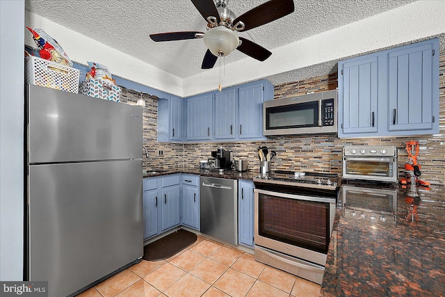 14 136th St Unit 101, Ocean City, MD 21842 - kitchen featuring stainless steel appliances, blue cabinetry, a textured ceiling, decorative backsplash, and light tile patterned floors