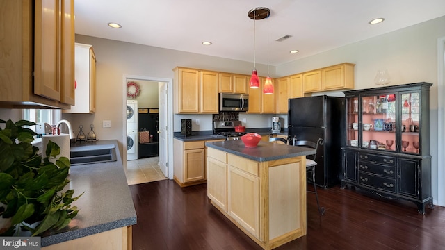 5510 Haverhill Ln, Doylestown, PA 18902 - kitchen with stainless steel appliances, light brown cabinetry, stacked washer and clothes dryer, dark countertops, and dark wood-style floors