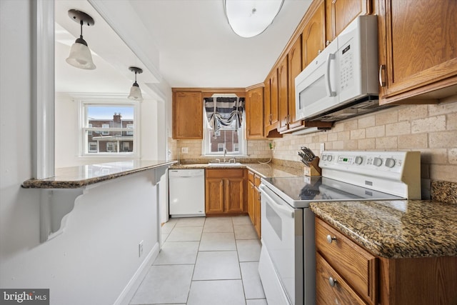 236 Lynn Rd, Ridley Park, PA 19078 - kitchen featuring white appliances, brown cabinets, backsplash, light tile patterned floors, and dark stone counters