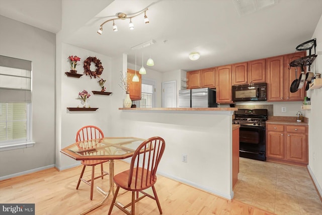 2044 Astilbe Way Unit 2044, Odenton, MD 21113 - kitchen featuring black appliances, brown cabinetry, pendant lighting, light wood finished floors, and a peninsula