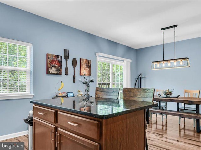 44 Munro Rd, Newark, DE 19711 - kitchen with light wood-style flooring, hanging light fixtures, a center island, and dark stone countertops