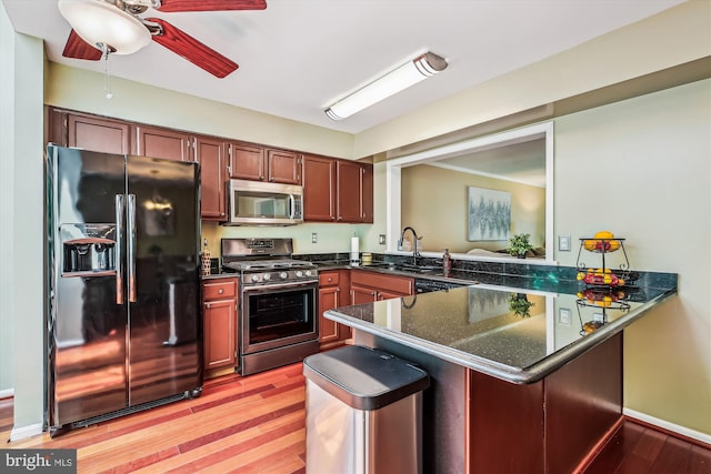 14329 Long Channel Dr, Germantown, MD 20874 - kitchen with appliances with stainless steel finishes, a peninsula, a ceiling fan, light wood-style floors, and dark stone countertops