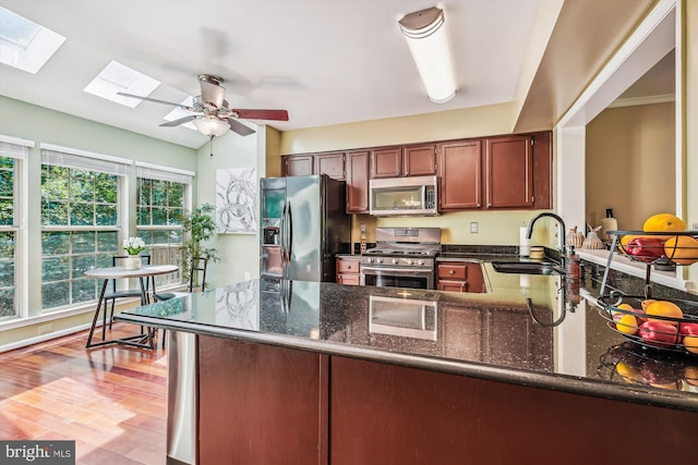 14329 Long Channel Dr, Germantown, MD 20874 - kitchen featuring appliances with stainless steel finishes, a peninsula, a skylight, and dark stone counters