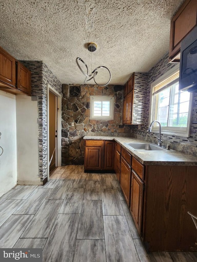 6222 Catalpha Rd, Baltimore, MD 21214 - kitchen with a textured ceiling, healthy amount of natural light, light wood finished floors, and brown cabinetry