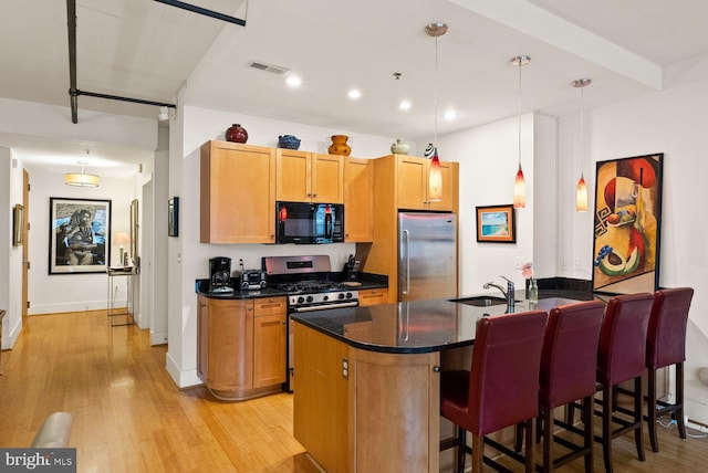 2328 Champlain St NW Unit 101, Washington, DC 20009 - kitchen with appliances with stainless steel finishes, light wood-style floors, a peninsula, a kitchen bar, and hanging light fixtures