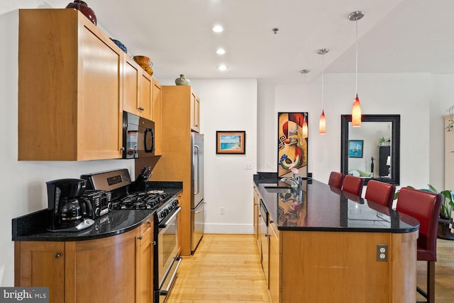 2328 Champlain St NW Unit 101, Washington, DC 20009 - kitchen with appliances with stainless steel finishes, light wood-type flooring, a kitchen bar, dark stone countertops, and recessed lighting