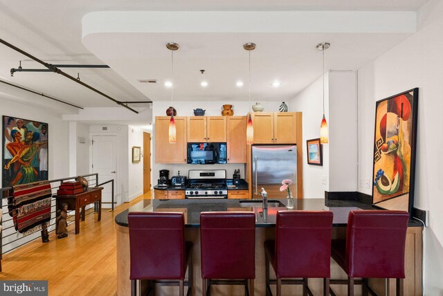 2328 Champlain St NW Unit 101, Washington, DC 20009 - kitchen with stainless steel appliances, dark countertops, a peninsula, a breakfast bar, and recessed lighting