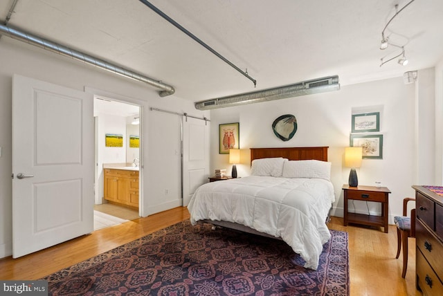 2328 Champlain St NW Unit 101, Washington, DC 20009 - bedroom featuring light wood finished floors, a barn door, ensuite bath, and track lighting
