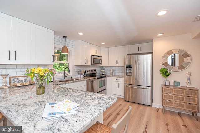 120 Robin Hood, Ocean Pines, MD 21811 - kitchen with appliances with stainless steel finishes, a peninsula, light stone countertops, light wood-style floors, and white cabinetry