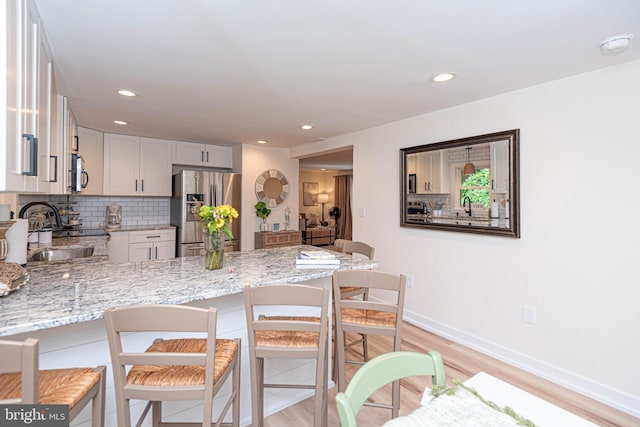 120 Robin Hood, Ocean Pines, MD 21811 - kitchen with appliances with stainless steel finishes, a peninsula, light stone countertops, light wood finished floors, and tasteful backsplash