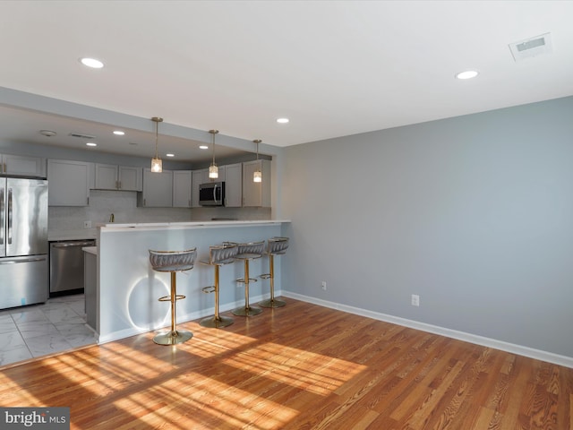 8175 Stone Bridge Rd, Greencastle, PA 17225 - kitchen featuring appliances with stainless steel finishes, gray cabinets, a breakfast bar, a peninsula, and light countertops