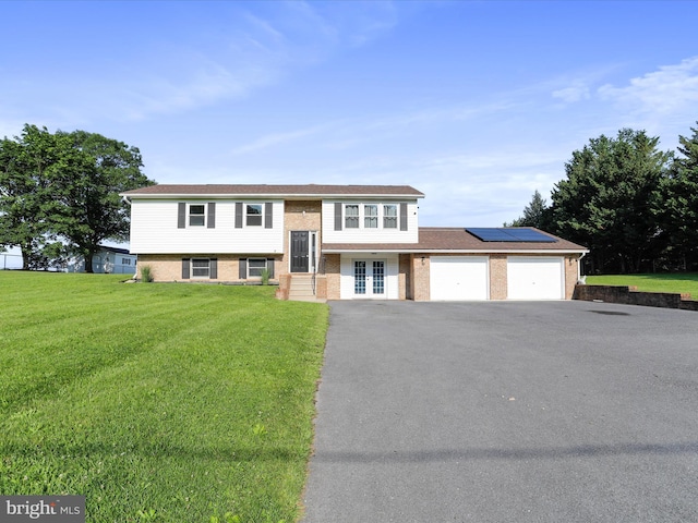 8175 Stone Bridge Rd, Greencastle, PA 17225 - bi-level home featuring a garage, roof mounted solar panels, a front lawn, driveway, and brick siding