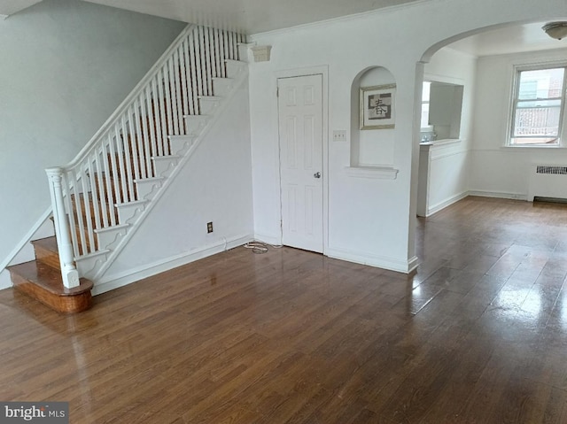 1420 Magee Ave, Philadelphia, PA 19111 - unfurnished living room featuring radiator heating unit, wood finished floors, stairs, arched walkways, and ornamental molding