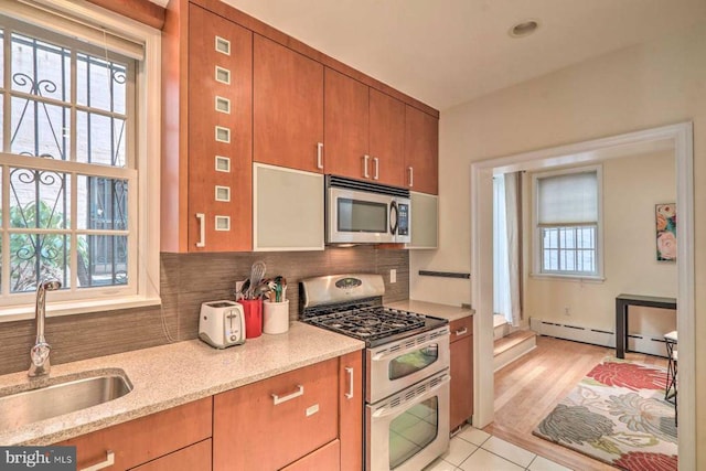1831MUTLI-UNIT Spruce St, Philadelphia, PA 19103 - kitchen featuring appliances with stainless steel finishes, backsplash, light stone counters, a baseboard heating unit, and brown cabinetry