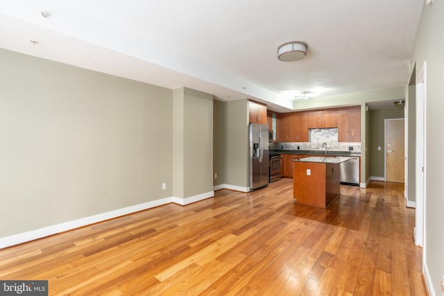 910 M St NW Unit 708, Washington, DC 20001 - kitchen with stainless steel appliances, backsplash, light wood-style floors, a center island, and brown cabinets