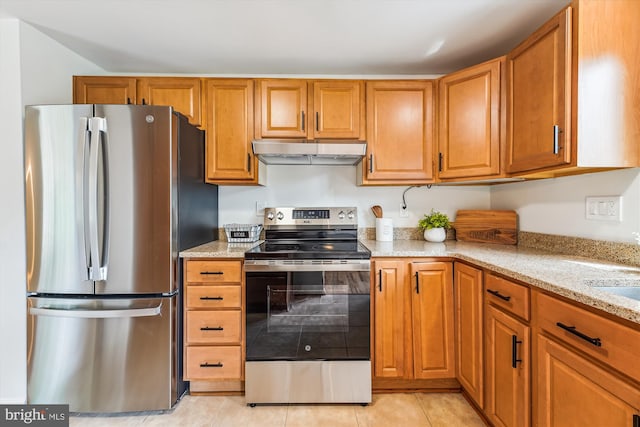 4376 Rock Ct, Waldorf, MD 20602 - kitchen featuring stainless steel appliances, under cabinet range hood, light stone counters, light tile patterned flooring, and brown cabinets