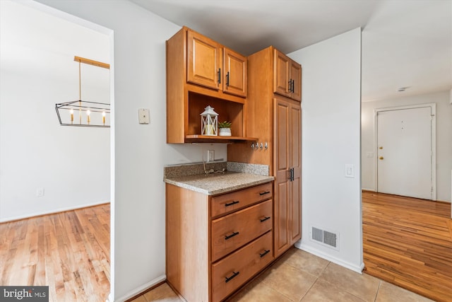 4376 Rock Ct, Waldorf, MD 20602 - kitchen featuring light stone counters, open shelves, light wood finished floors, and brown cabinets