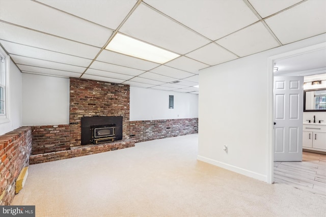 4376 Rock Ct, Waldorf, MD 20602 - unfurnished living room featuring a wood stove, light colored carpet, a paneled ceiling, and brick wall