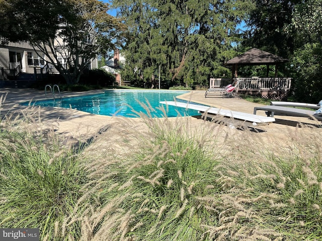 2424 Stanwick Rd, Phoenix, MD 21131 - swimming pool with a gazebo, a diving board, a wooden deck, and view of wooded area