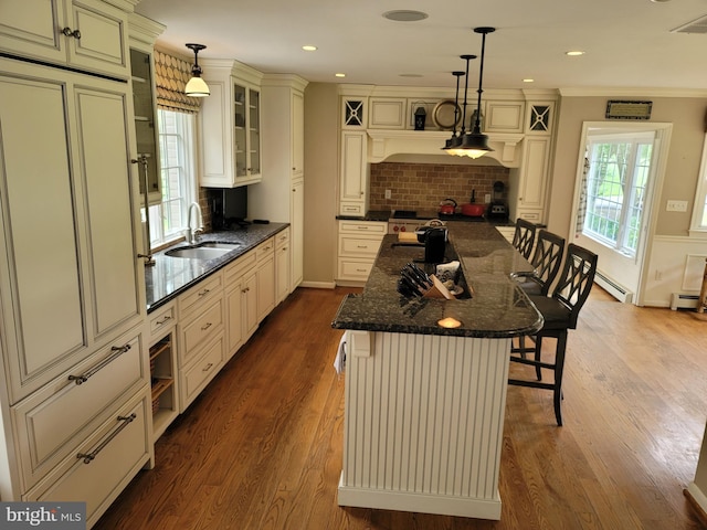 2424 Stanwick Rd, Phoenix, MD 21131 - kitchen with cream cabinetry, a breakfast bar, decorative backsplash, dark wood-style floors, and crown molding
