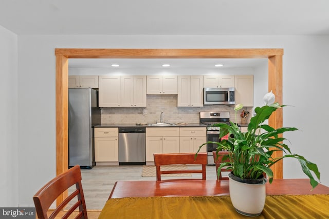 1117 Regina Dr, Baltimore, MD 21227 - kitchen with stainless steel appliances, light wood-style floors, decorative backsplash, dark countertops, and recessed lighting