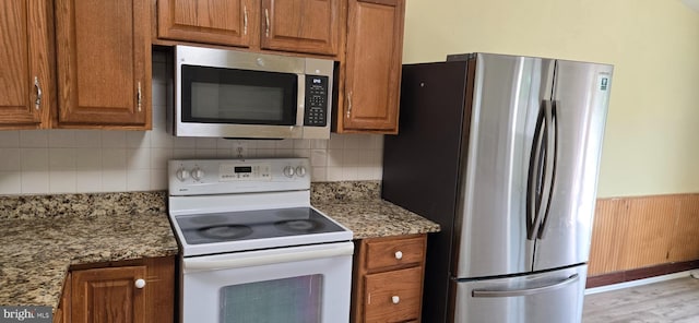 350 Juniper Ct, Herndon, VA 20170 - kitchen featuring appliances with stainless steel finishes, brown cabinets, light stone counters, and decorative backsplash