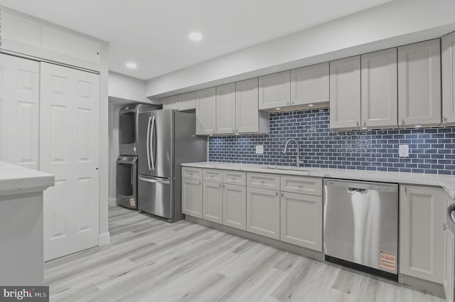 2 Stonehenge Cir Unit 2A-2, Baltimore, MD 21208 - kitchen with appliances with stainless steel finishes, estacked washer and dryer, light wood-style flooring, tasteful backsplash, and light stone counters