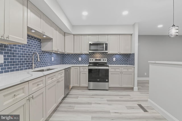 2 Stonehenge Cir Unit 2A-2, Baltimore, MD 21208 - kitchen with stainless steel appliances, backsplash, light stone counters, light wood finished floors, and pendant lighting