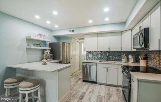 405 Ocean Ave Unit 110, Wildwood, NJ 08260 - kitchen featuring stainless steel appliances, a peninsula, a breakfast bar, backsplash, and light wood-style flooring