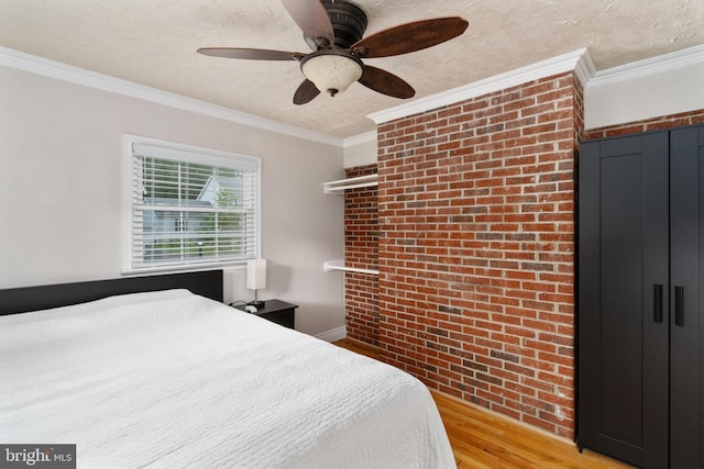 5379 Payne Dr, King George, VA 22485 - bedroom featuring light wood-style flooring, a textured ceiling, crown molding, brick wall, and a ceiling fan