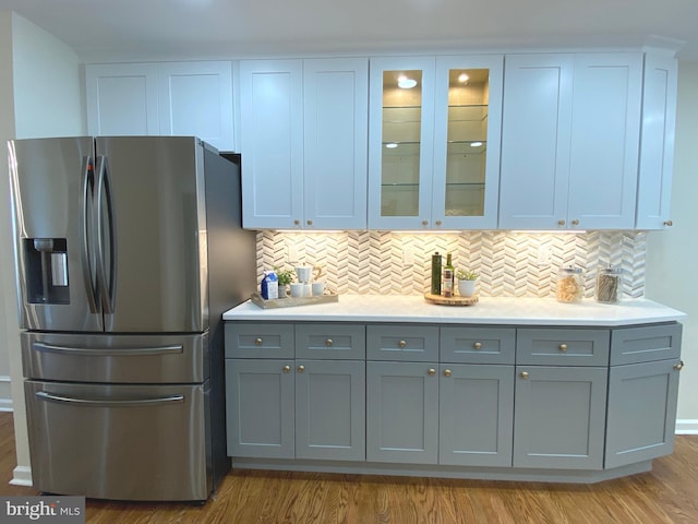 3103 Woodhaven Dr, Cinnaminson, NJ 08077 - kitchen with stainless steel refrigerator with ice dispenser, light wood-style flooring, light countertops, tasteful backsplash, and glass insert cabinets
