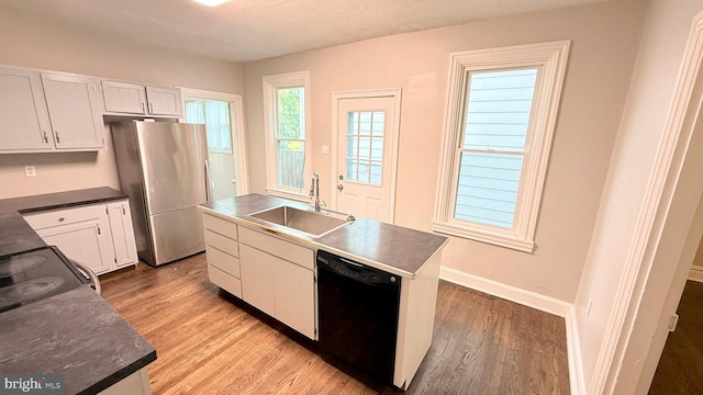 421 N Hanover St, Carlisle, PA 17013 - kitchen with dishwasher, freestanding refrigerator, light wood-type flooring, dark countertops, and white cabinets