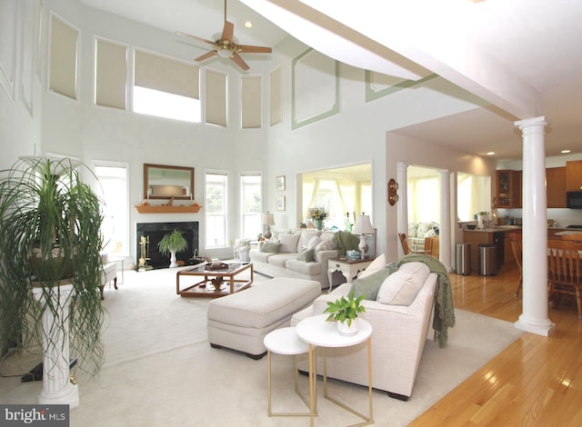 802 Chesapeake Ct, Newark, DE 19702 - living room with decorative columns, a ceiling fan, light wood-style floors, a fireplace, and a towering ceiling