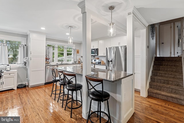 202 E Franklin Ave, Edgewater Park, NJ 08010 - kitchen with appliances with stainless steel finishes, a breakfast bar, light wood finished floors, ornamental molding, and dark stone counters