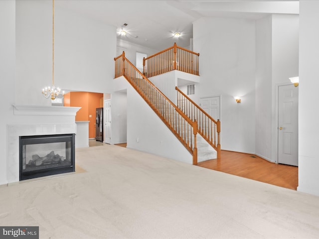2135 Vittoria Ct Unit 33, Bowie, MD 20721 - unfurnished living room featuring high vaulted ceiling, carpet flooring, stairway, a multi sided fireplace, and a chandelier