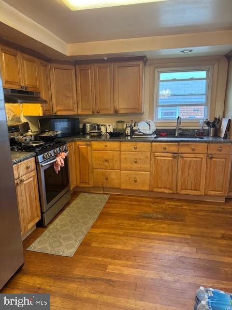 418 Jefferson St, Lansdale, PA 19446 - kitchen with stainless steel gas range, under cabinet range hood, black microwave, dark countertops, and wood finished floors
