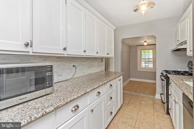 5100 Eugene Ave, Baltimore, MD 21206 - kitchen with appliances with stainless steel finishes, tasteful backsplash, white cabinets, under cabinet range hood, and light tile patterned flooring