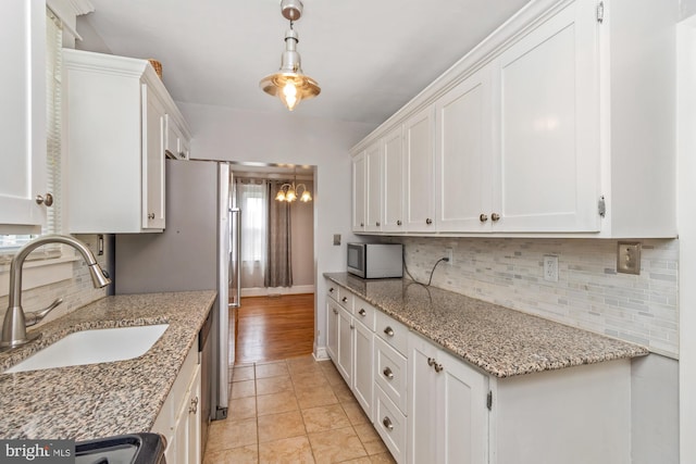 5100 Eugene Ave, Baltimore, MD 21206 - kitchen with stainless steel microwave, white cabinets, decorative backsplash, hanging light fixtures, and light tile patterned flooring