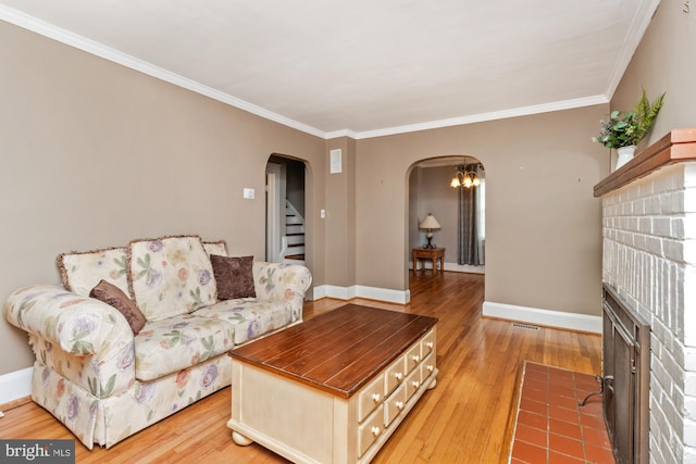 5100 Eugene Ave, Baltimore, MD 21206 - living room with arched walkways, ornamental molding, light wood-style floors, a brick fireplace, and stairway