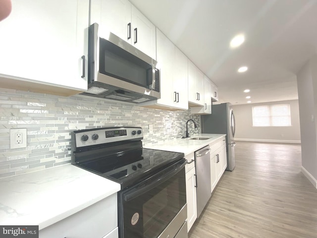 1319 Rainer Rd, Brookhaven, PA 19015 - kitchen featuring appliances with stainless steel finishes, recessed lighting, white cabinetry, light wood-style flooring, and tasteful backsplash