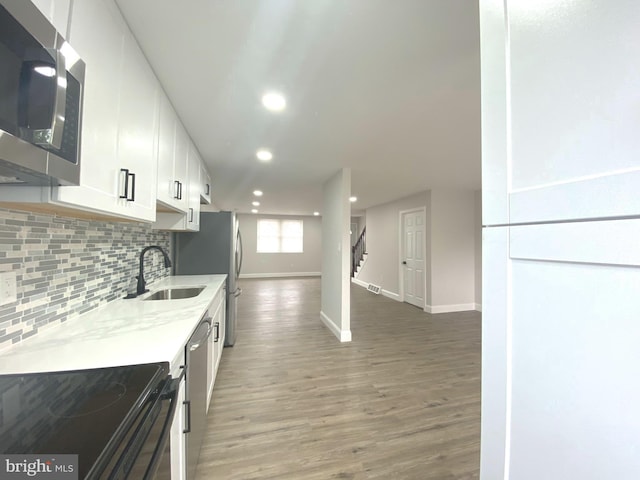 1319 Rainer Rd, Brookhaven, PA 19015 - kitchen with stainless steel appliances, recessed lighting, decorative backsplash, white cabinets, and light wood-style floors